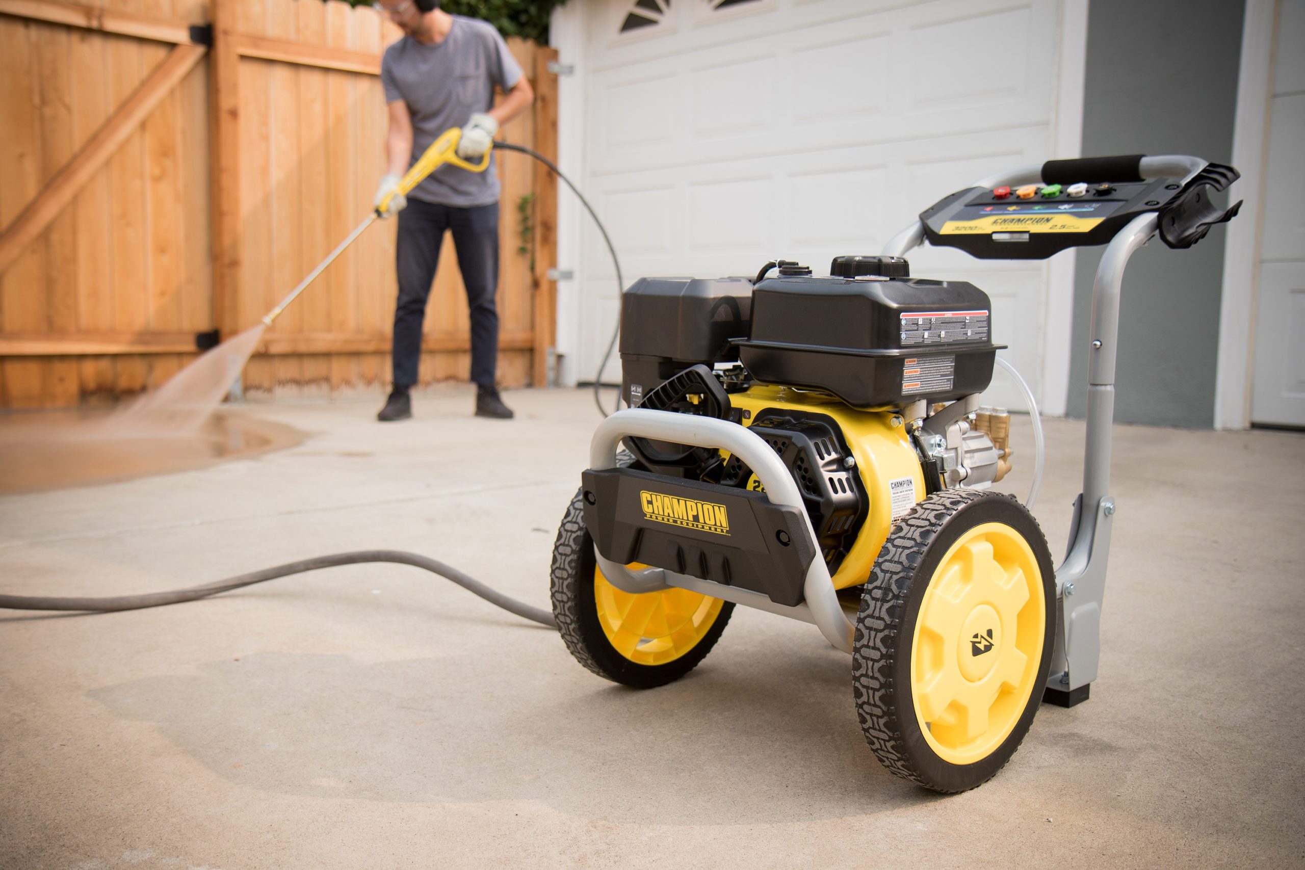 a man using a pressure washer on a driveway.